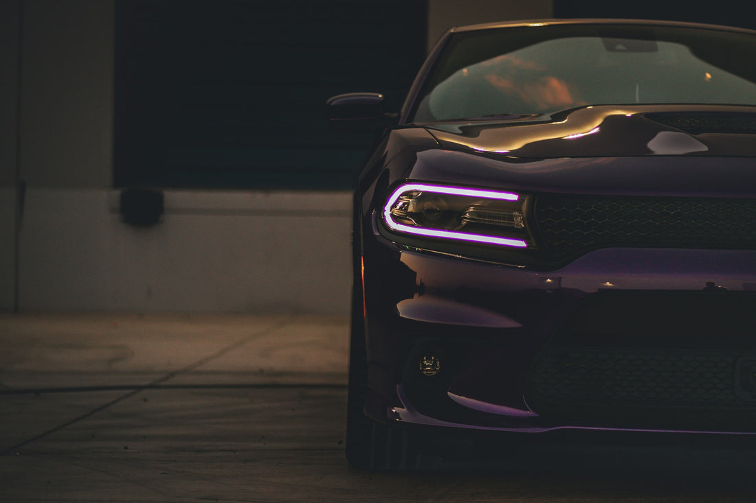 Front view of a dark purple car with modern LED headlights in a dimly lit urban area.