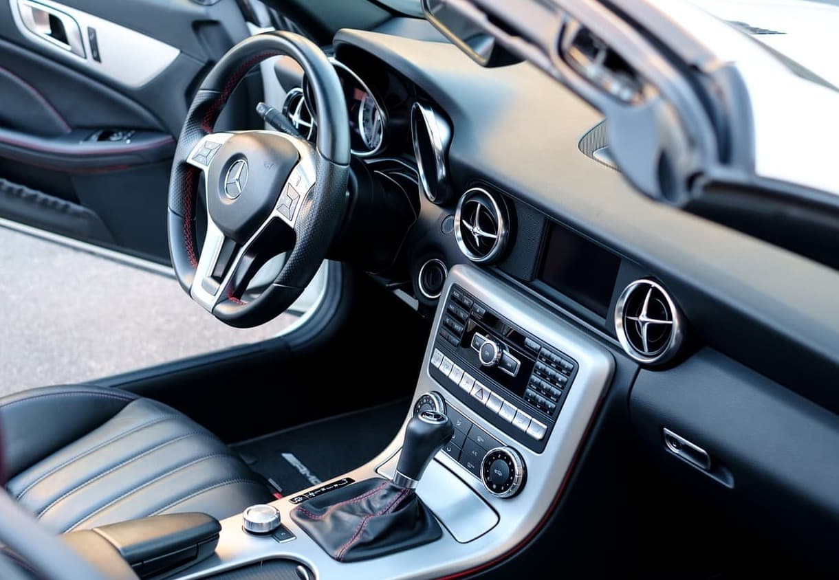 Close-up of a luxury car dashboard with leather interior and chrome steering wheel.