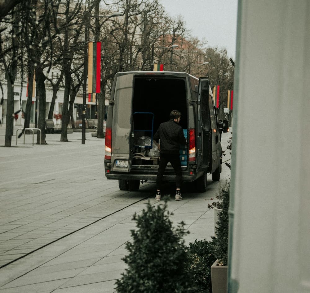 Delivery person unloading packages from a van on a city street.