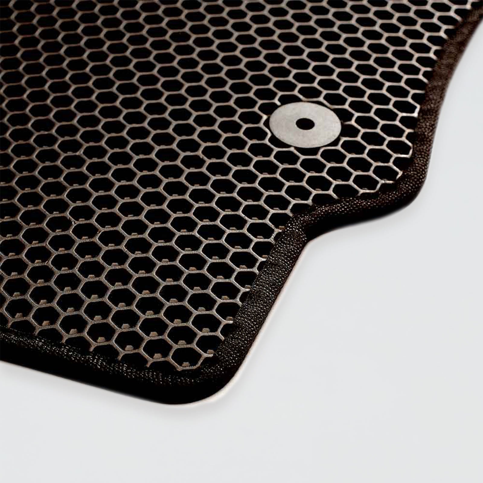 Close-up of a black hexagonal-patterned mat with a metallic button detail.