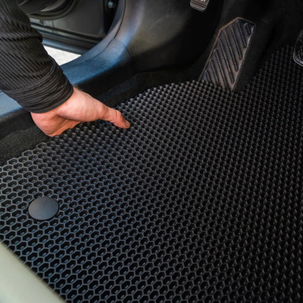 Universal Easy-Trim black car floor mat being adjusted for a perfect fit in a car.