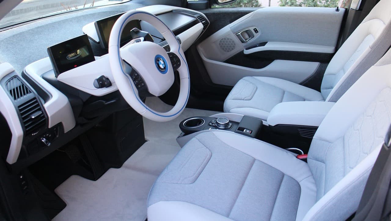 Modern BMW interior with light upholstery and dual screens on the dashboard.