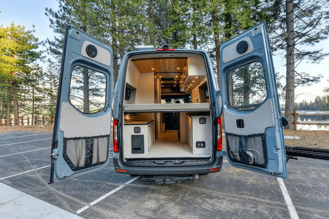 Modern camper van with open rear doors showing luxury interior design and wooden finish.
