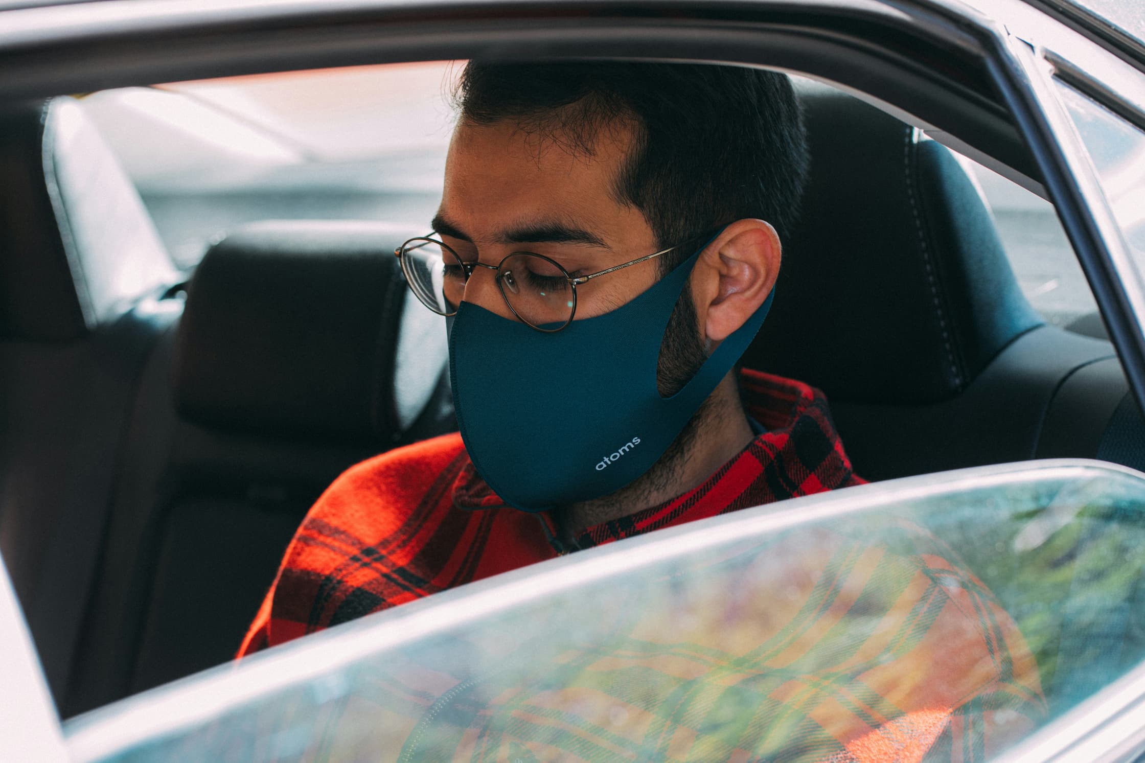 Man wearing a blue protective face mask while sitting inside a car.