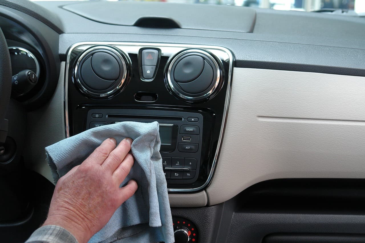 Hand drying a car dashboard with a microfiber cloth after washing the interior.