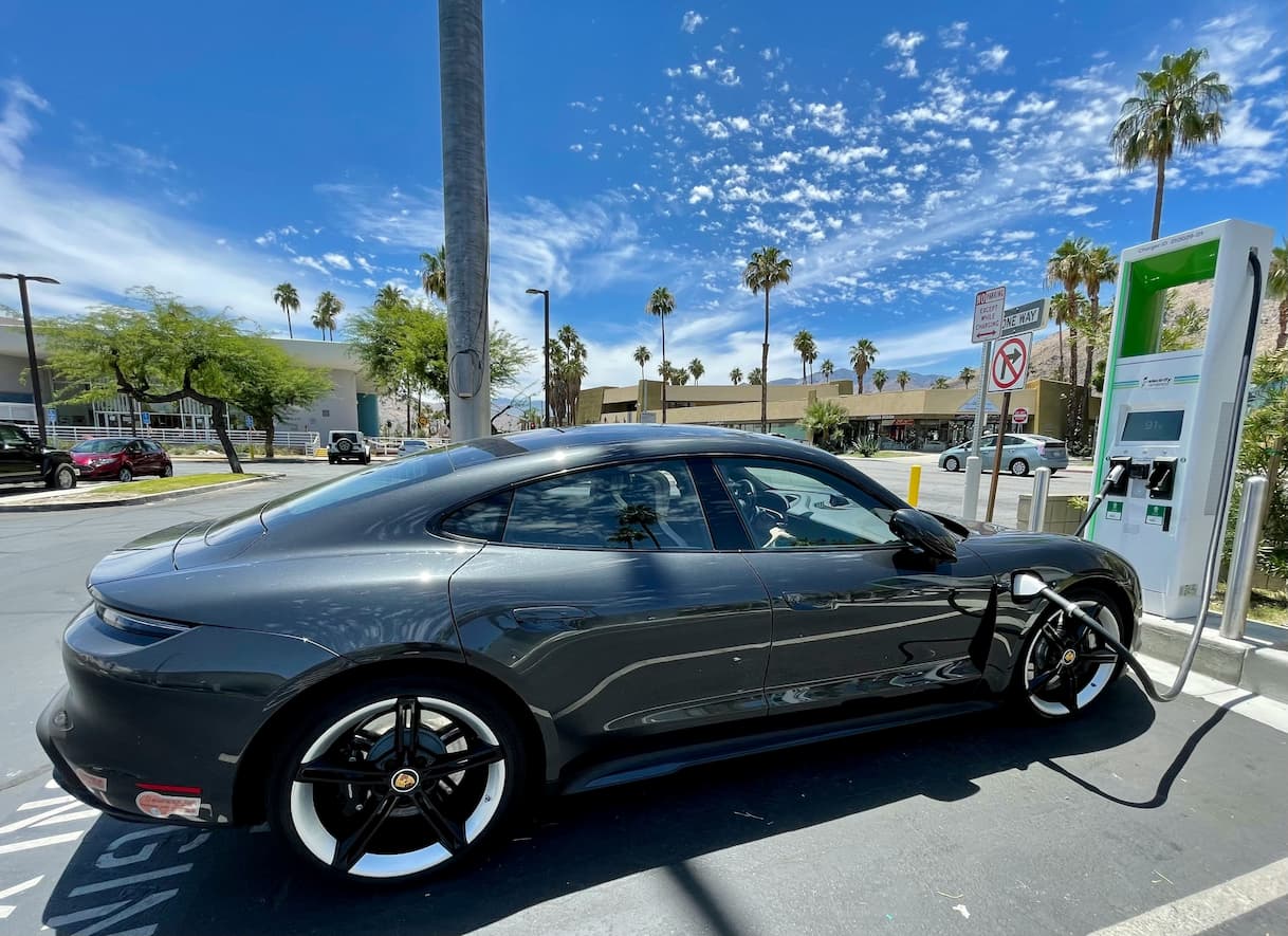 Electric vehicle parked at a charging station under a clear blue sky.