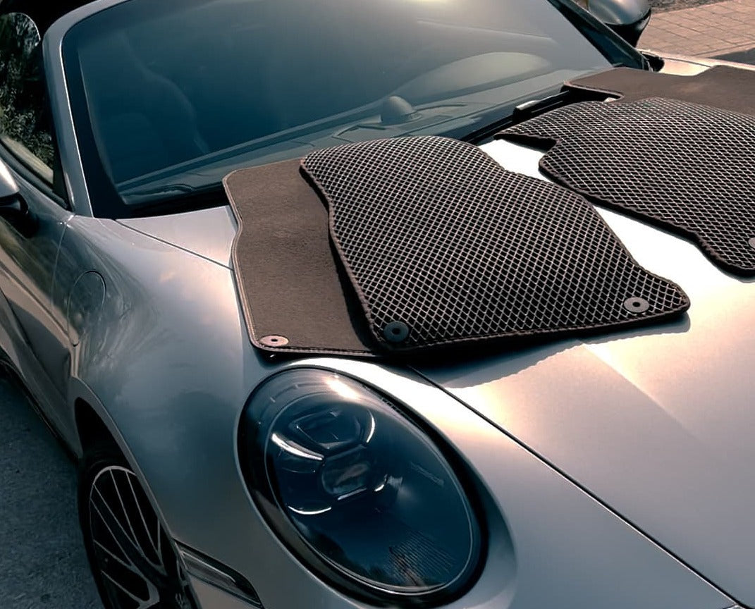 EVA car mats placed on the hood of a silver sports car under sunlight.