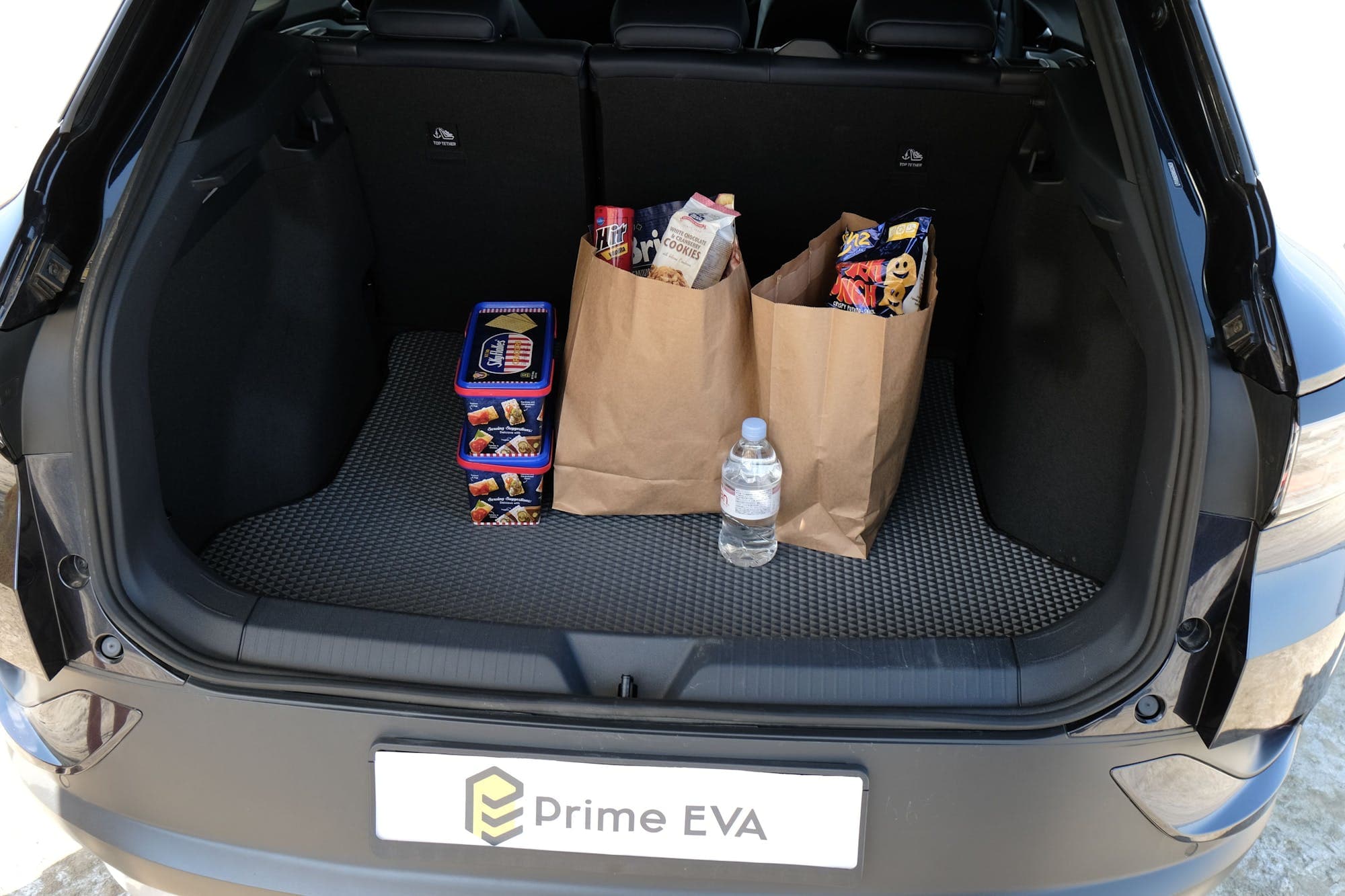 EVA trunk mat holding shopping bags and bottled water in a car boot.