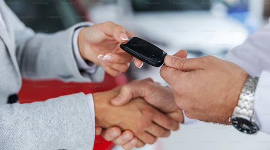 A close-up of hands exchanging a car key with a firm handshake.