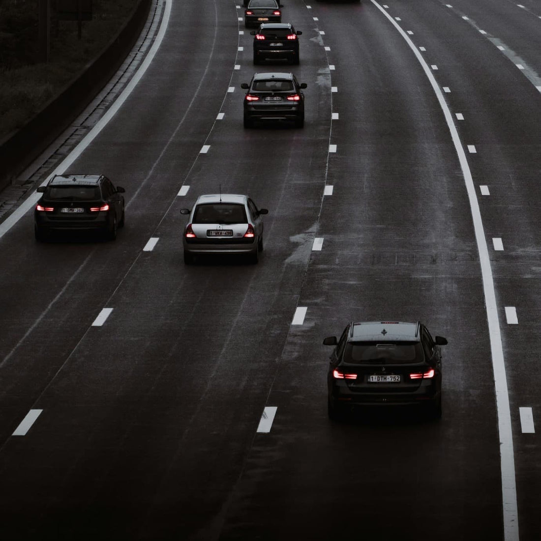 Highway traffic view showing multiple vehicles driving on a wet multi-lane road.