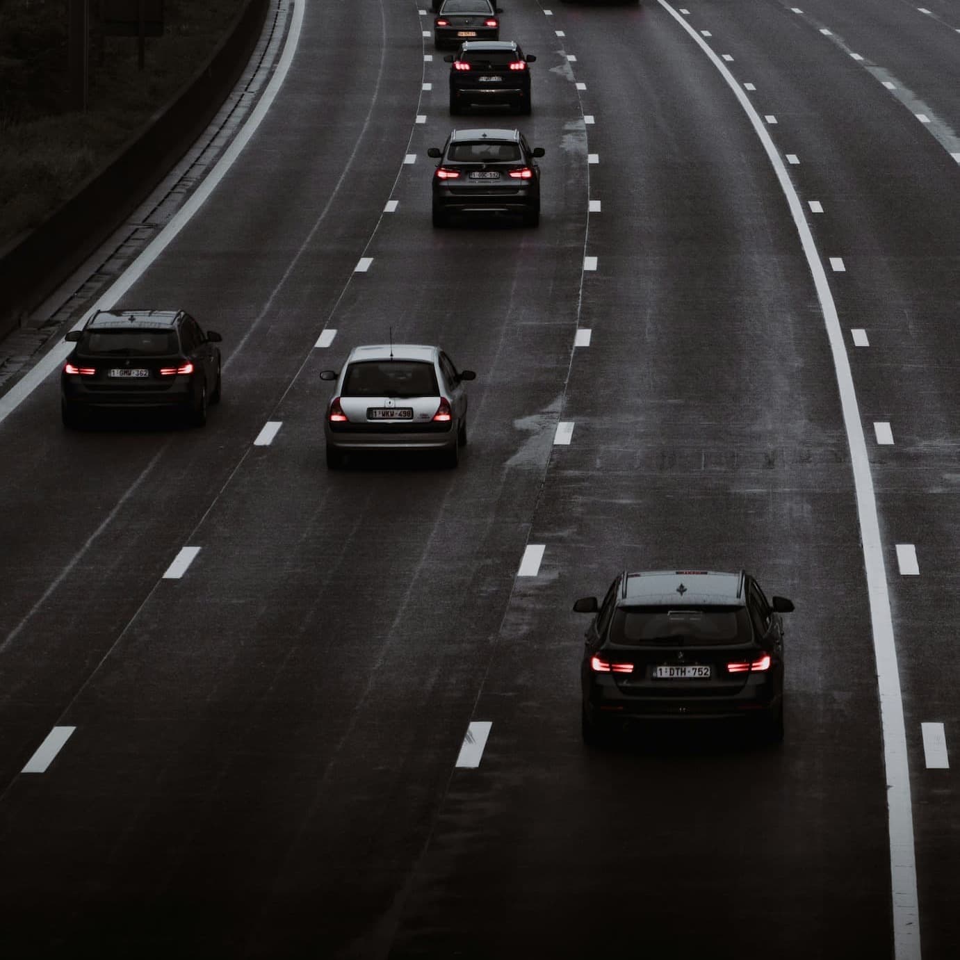Highway traffic view showing multiple vehicles driving on a wet multi-lane road.