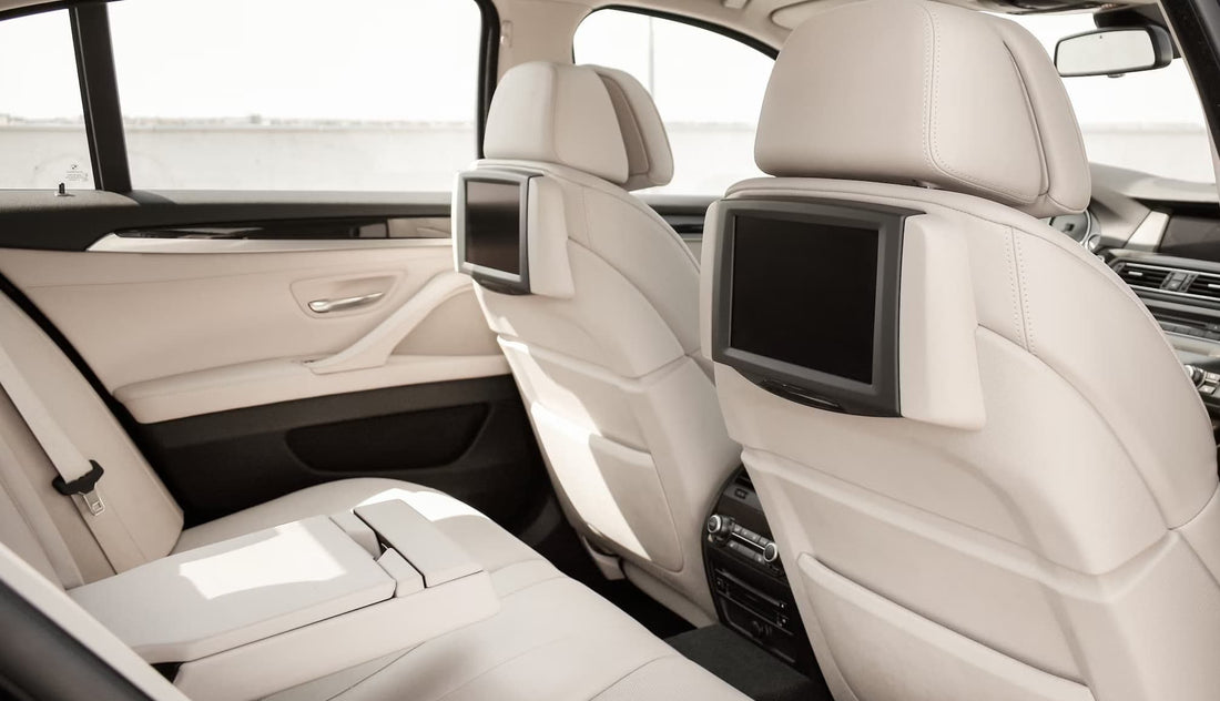 Luxury car interior with beige leather seats and entertainment screens on the backrests.