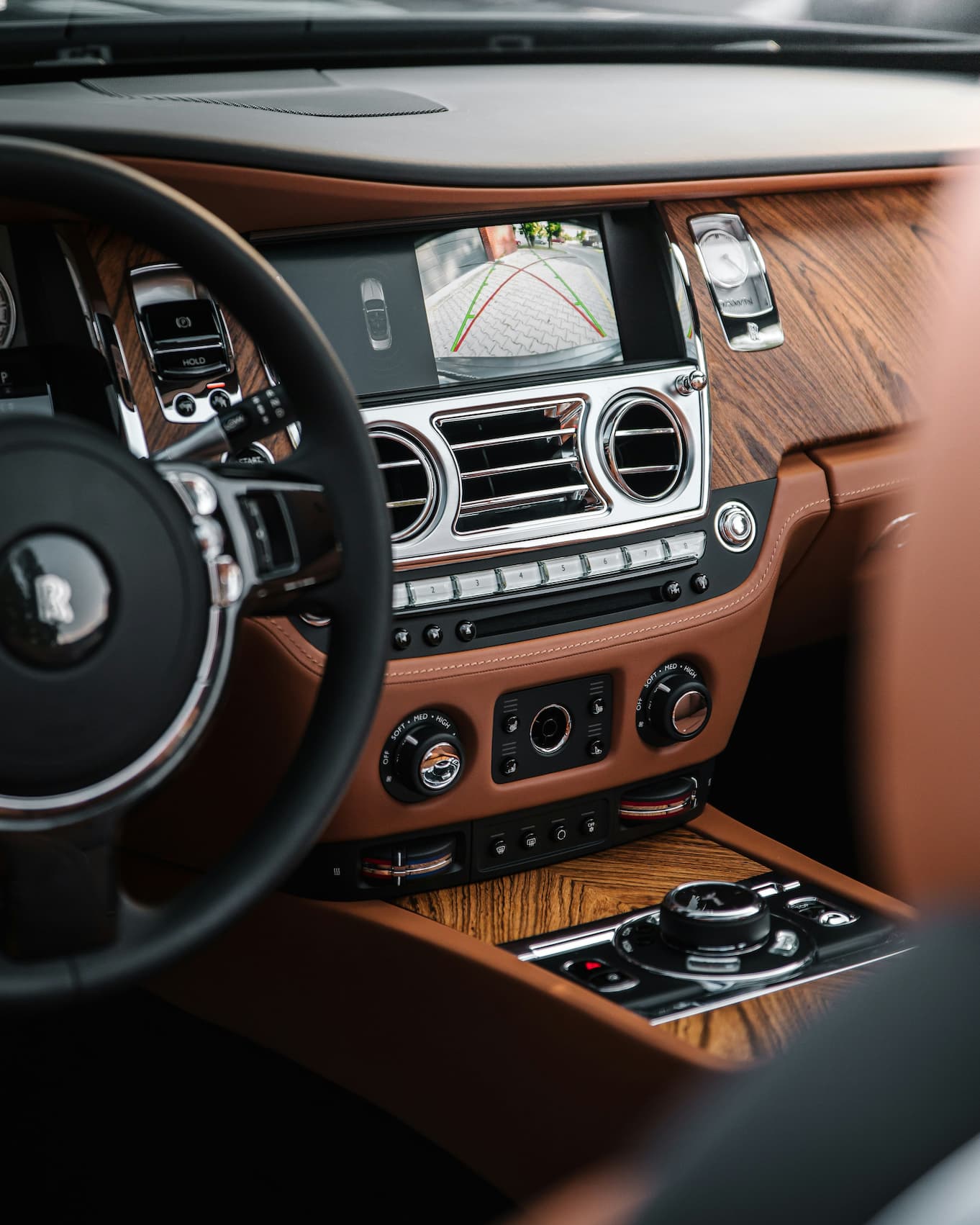 Luxury car interior with wood trim and a rear-view camera display showing parking guide lines.