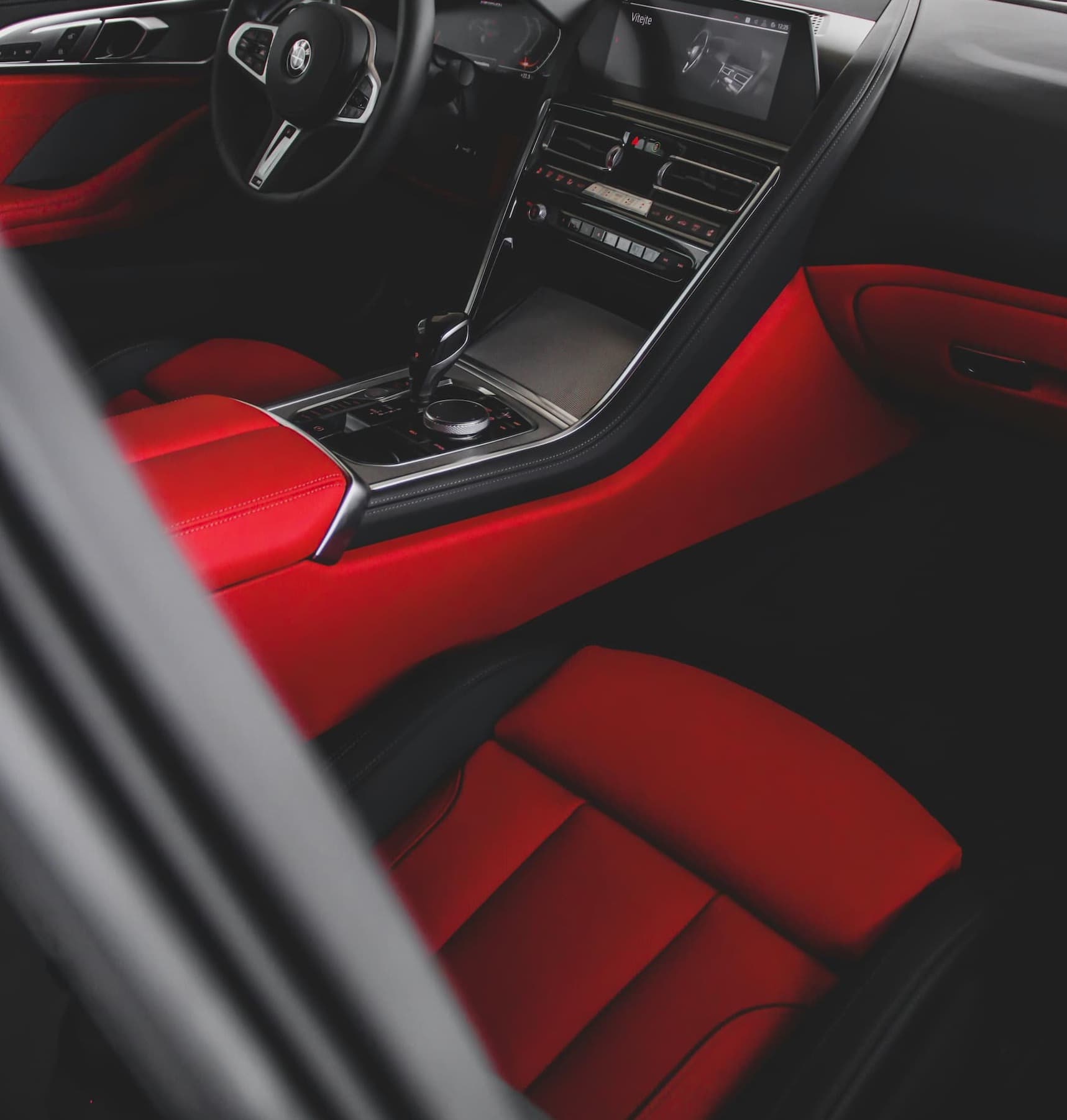Close-up of a luxury car interior with red leather seats and sleek dashboard design.