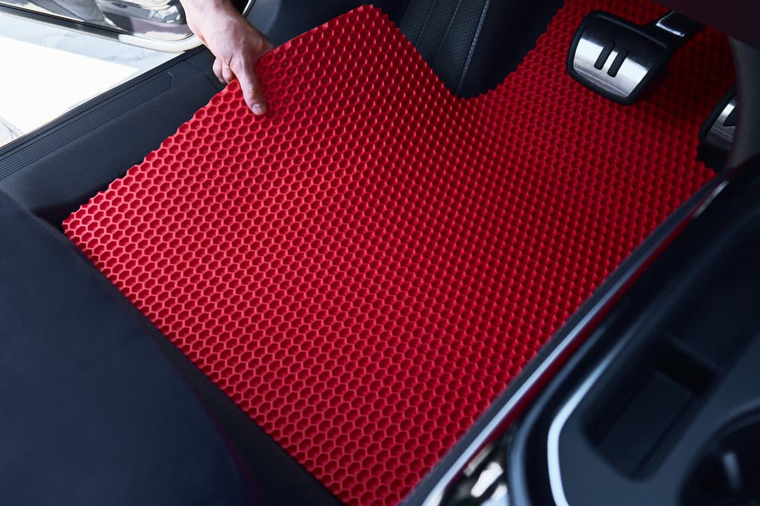 Red EVA car floor mat being installed inside the vehicle near the driver's pedals.