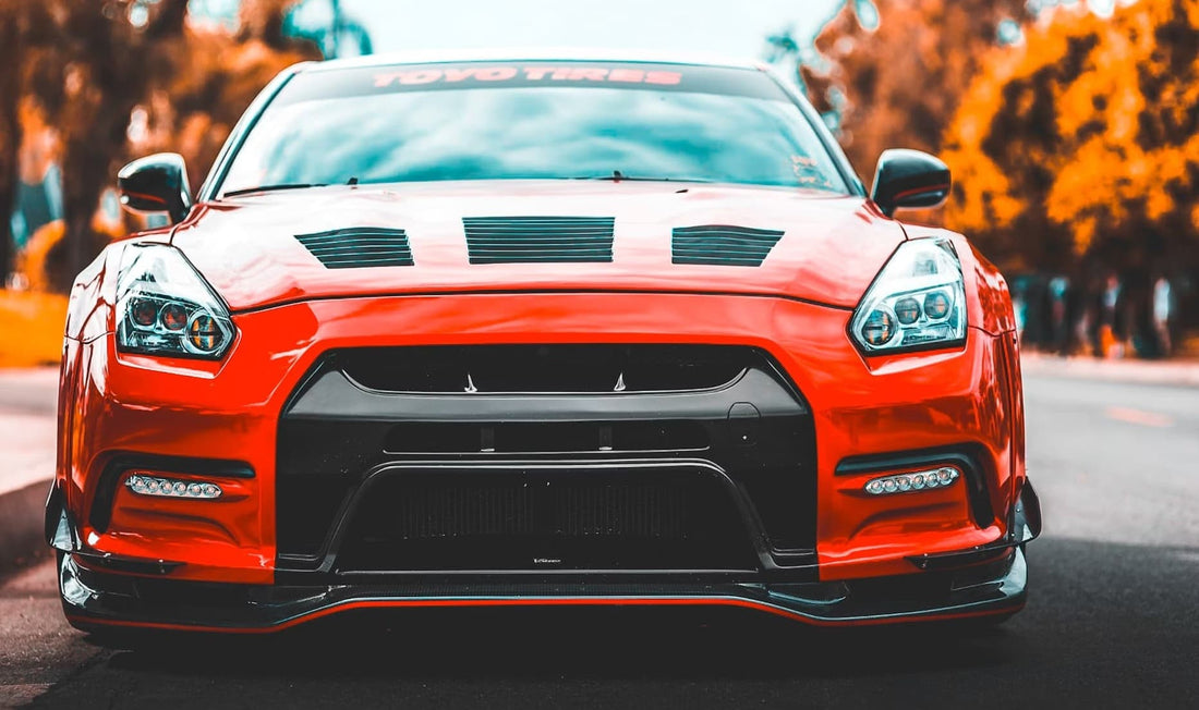 Front view of a red sports car with black accents and custom headlights.