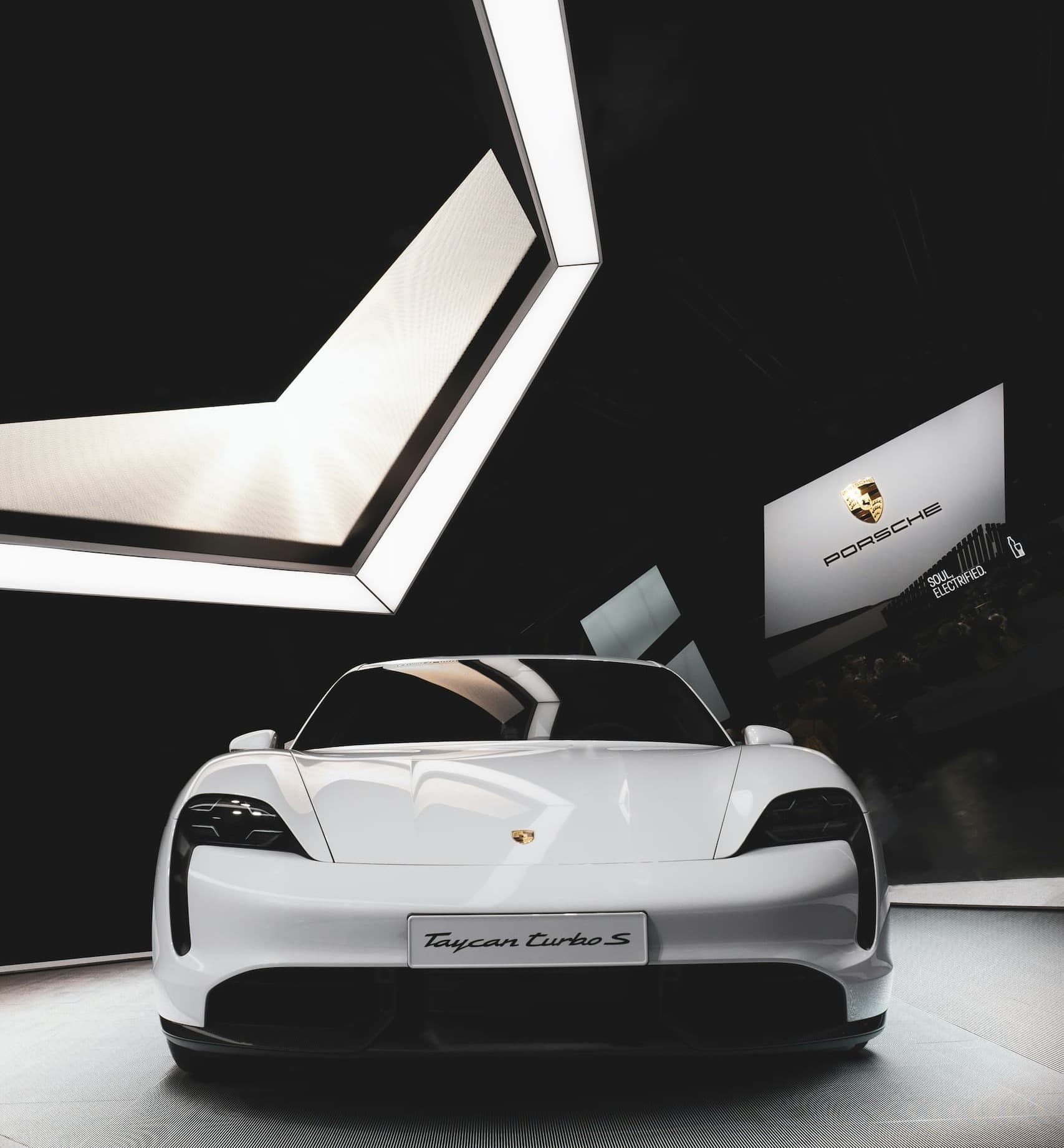 White luxury electric sports car displayed in modern showroom lighting.