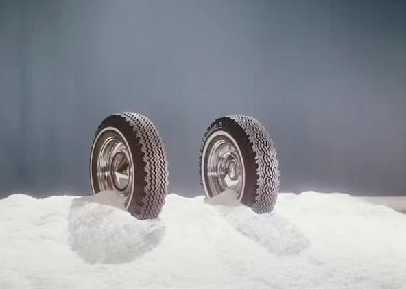 Two car tires partially buried in snow, highlighting their winter tread design.