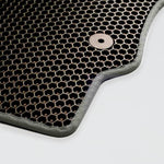 Close-up of a textured black rubber mat with a hexagonal pattern and a metal fastener.