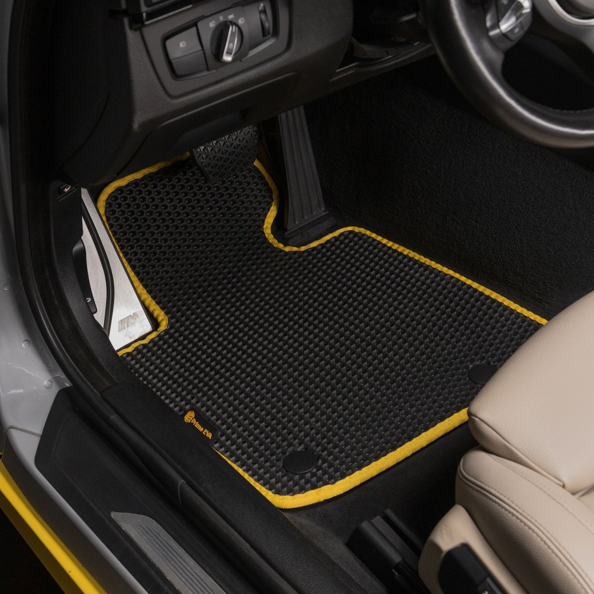 Black car floor mat with yellow trim, custom-fit for BMW interior.