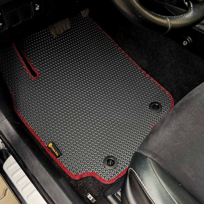 Close-up of a custom black car floor mat with red stitching in a Toyota RAV4 interior.