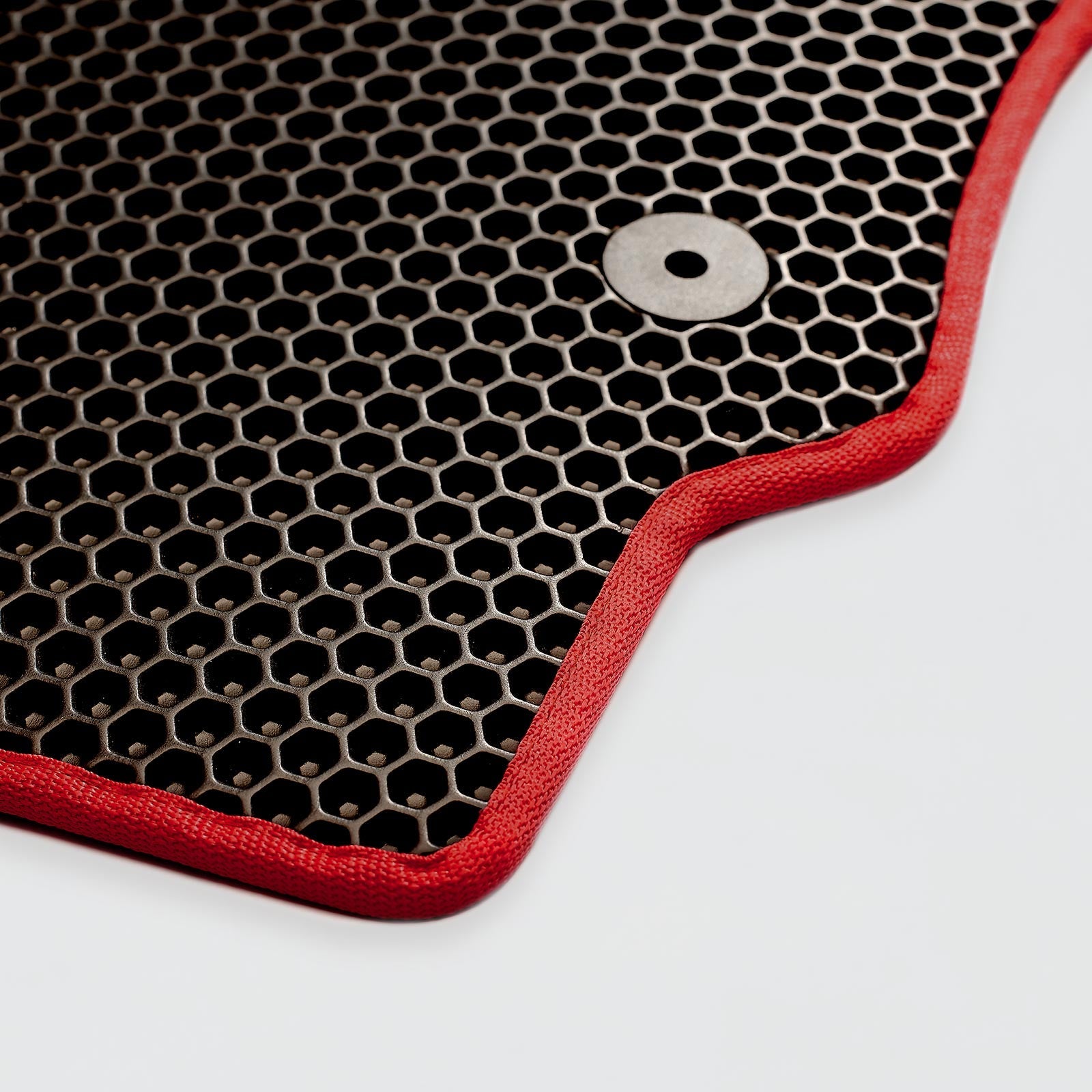 Close-up of a black honeycomb-pattern mat with red edges and a metal snap button.