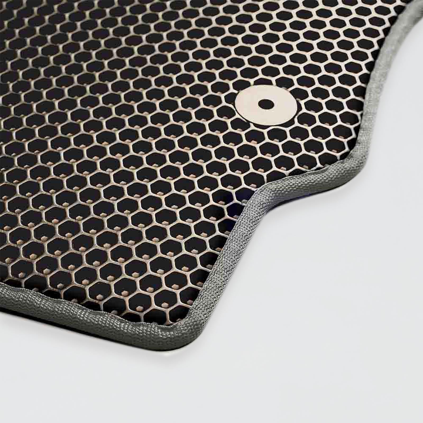 Close-up of a black textured honeycomb car mat with a metal grommet.