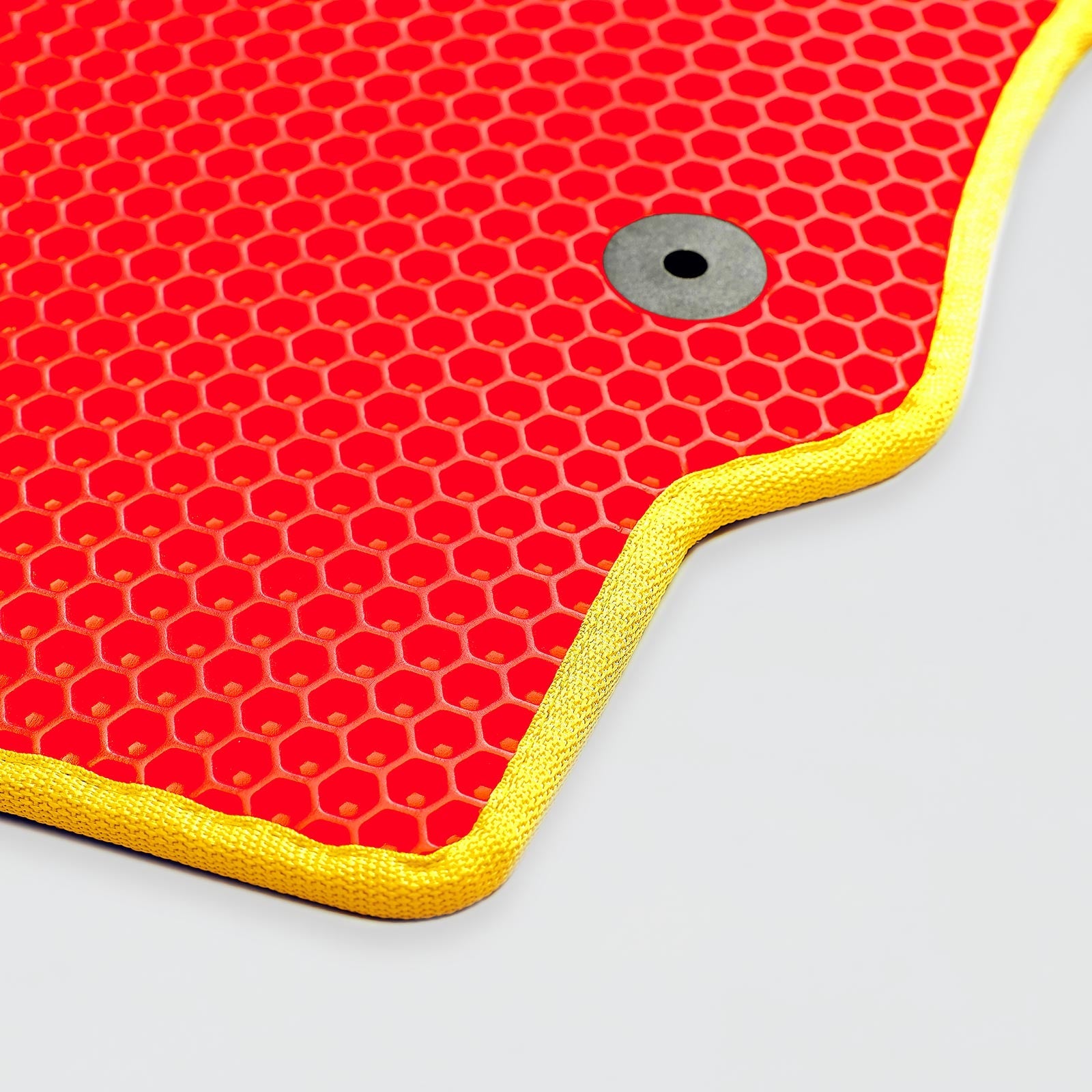 Red honeycomb-patterned mat with yellow edges and a metal grommet.
