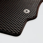 Black rubber car floor mat with a textured grid design and a circular grip hole