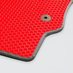 Close-up of a red textured mat with a honeycomb pattern and a silver grommet.