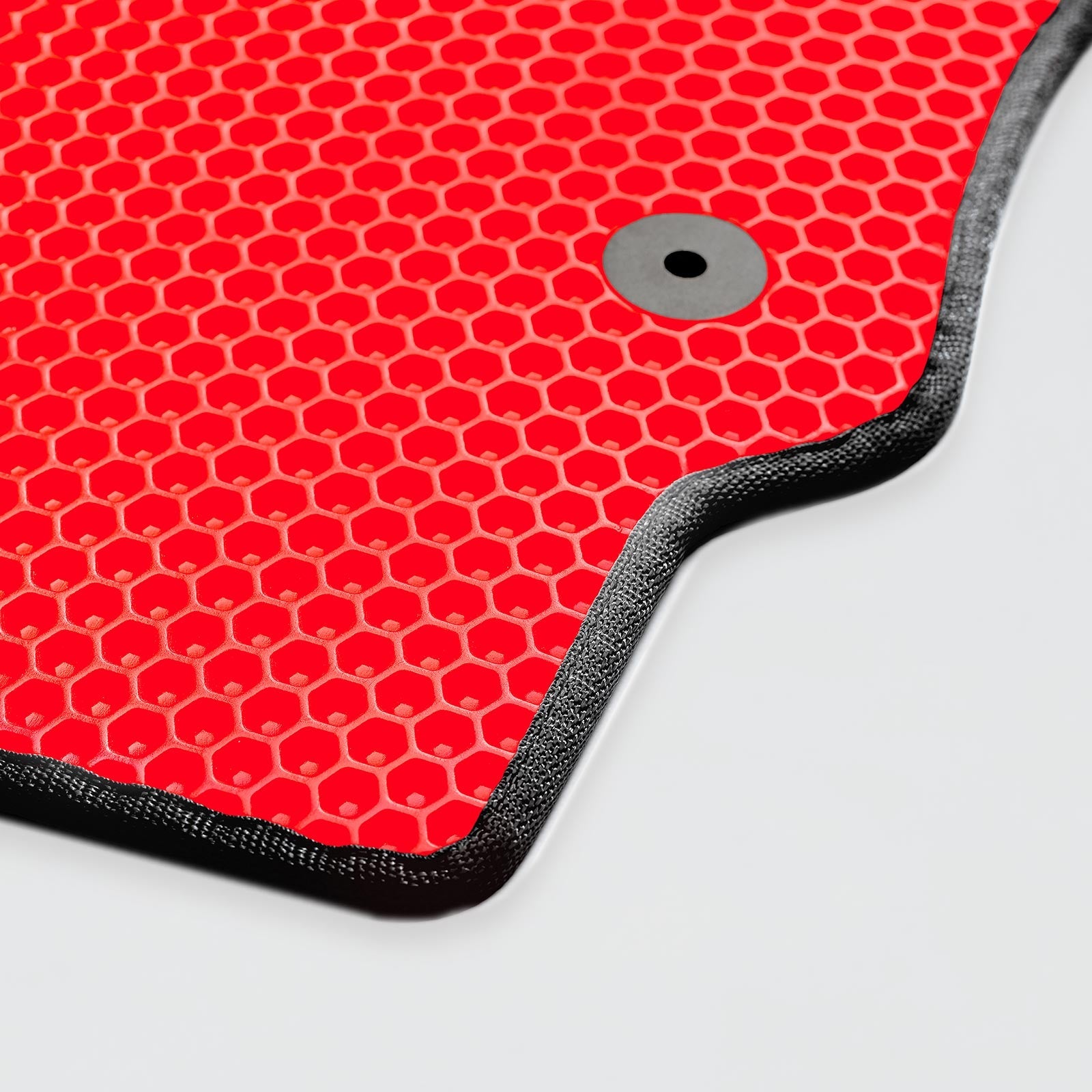 Close-up of a red textured mat with a black border and circular grommet.
