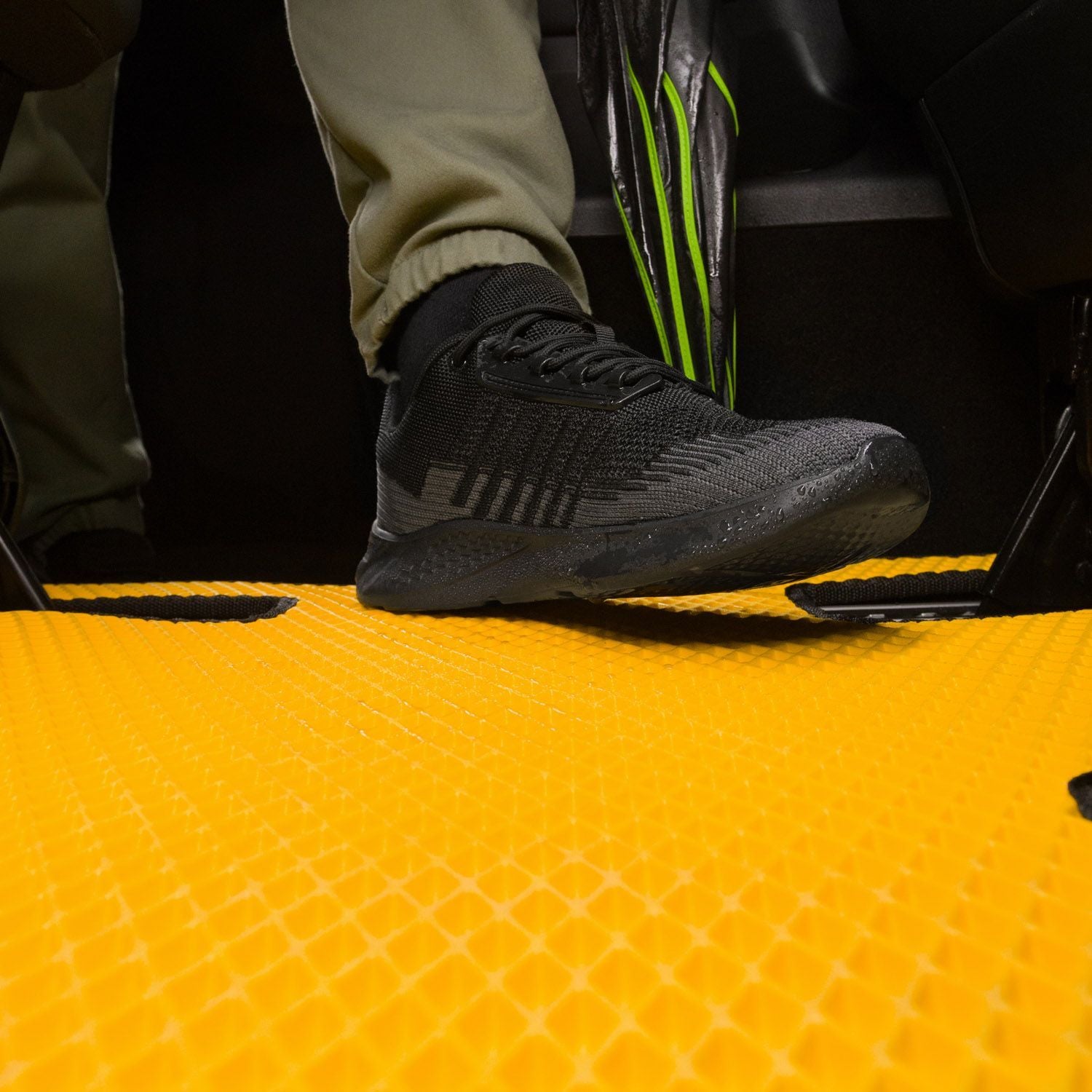 Close-up of a black shoe stepping on a yellow textured van mat, showing grip.