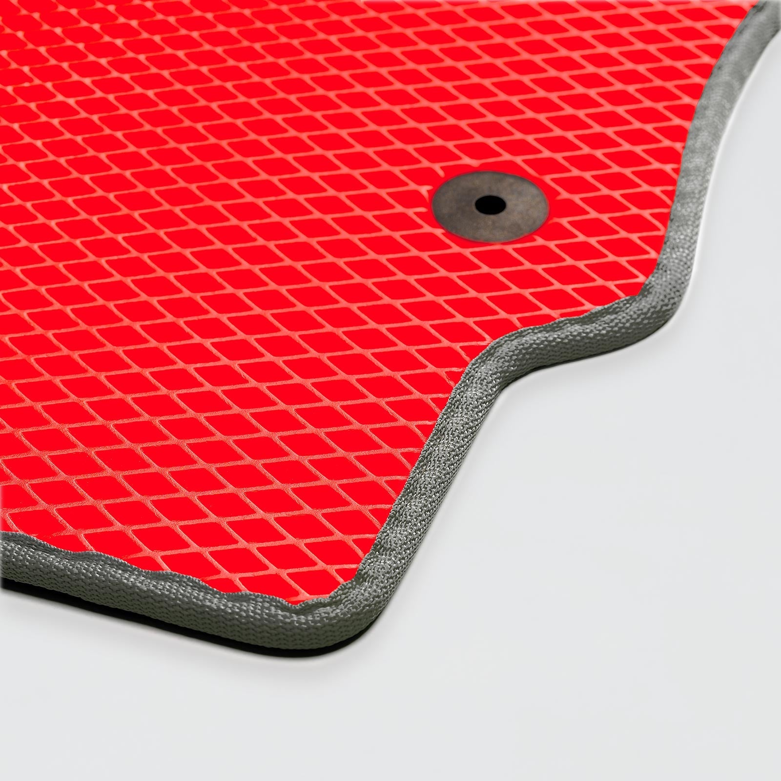 Close-up of a red textured rubber mat with a drainage hole and silver edge.