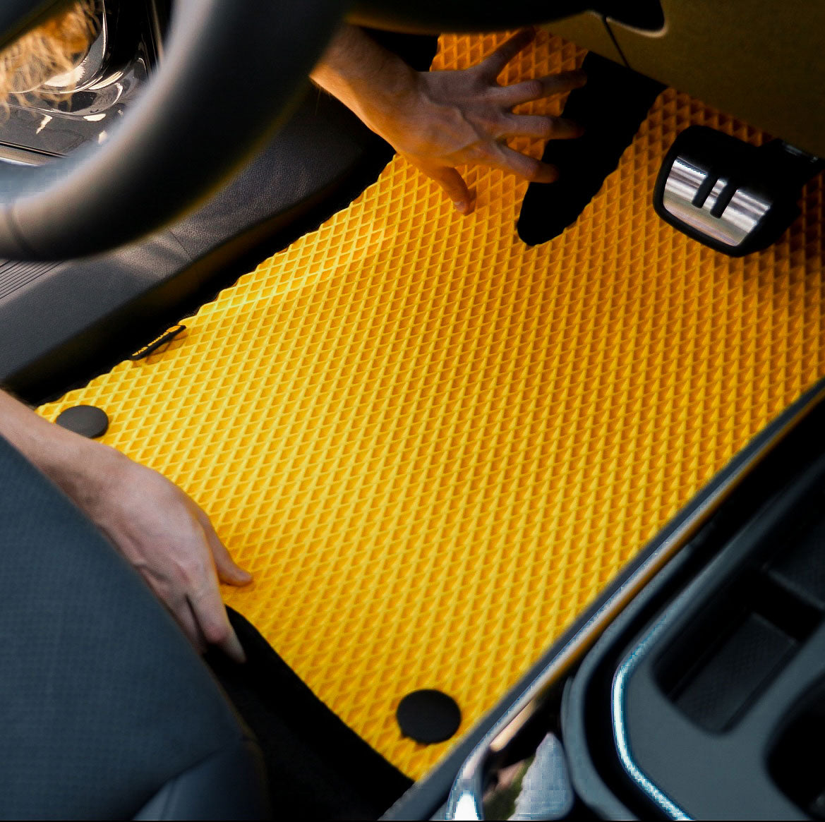 Person installing a yellow car floor mat
