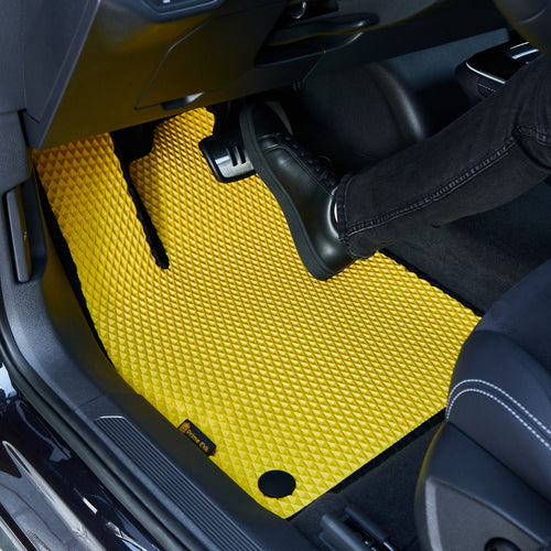 Stambiu planu - geltonas tekstūruotas automobilinis kilimėlis su pėda ant jo
