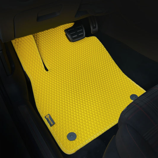 Žlutá rohož do auta s kosočtvercovou texturou v černém interiéru
